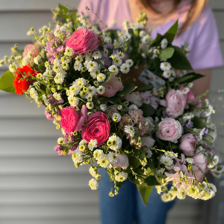 bouquets held in hand with white purple and pink flowers